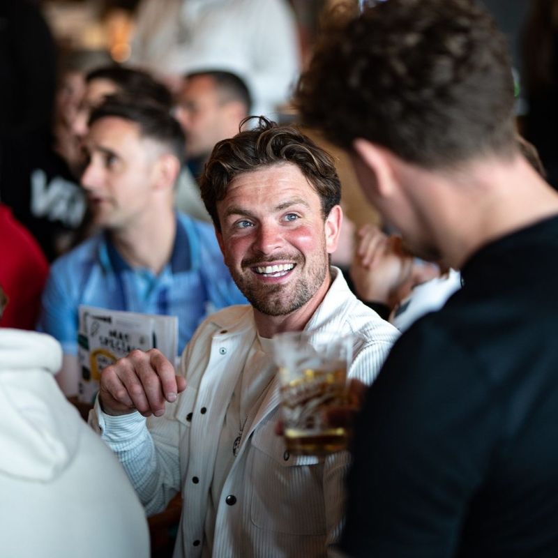 Two gentleman enjoying conversation over the boxing match. The pub is packed out with boxing fans.